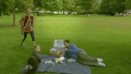 két ember nyugodtan piknikezik, közbe jön egy srác és felrúgra az ételüket