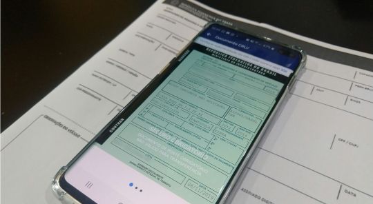 celular com documento do carro digital aberto sobre crlv impresso