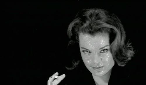 Gif from l'Enfer, actress Romy Schneider holds a cigarette, her makeup shimmering under pulsating light