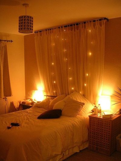 Hang a curtain behind a bed with string lights