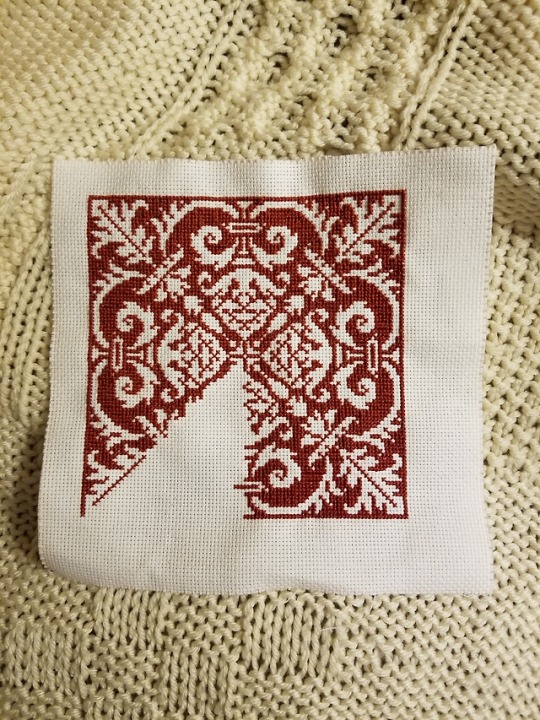 Cross stitch pattern, 7/8th of the way finished, in dark red thread