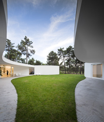 ombuarchitecture:<br /><br />House in Aroeira<br />Due to the absence of fences, the hexagonal shape of the plot is not clear and the ground blends with the surrounding pinewoods. The house occupies the maximal area of construction, concentric to the six-sided plot. Disposed round a courtyard to which every space converges, its peculiar form finds a precise boundary in the outline of the canopy. Service areas provide geometry and stability to the main spaces.<br />By Aires Mateus<br />Photos by FG+SG