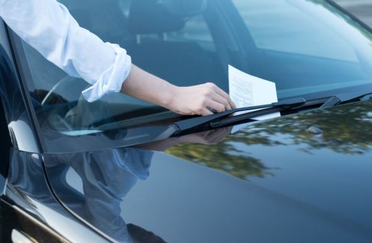 Homem pega advertência por escrito referente a multa leve ou média no para-brisa do carro 
