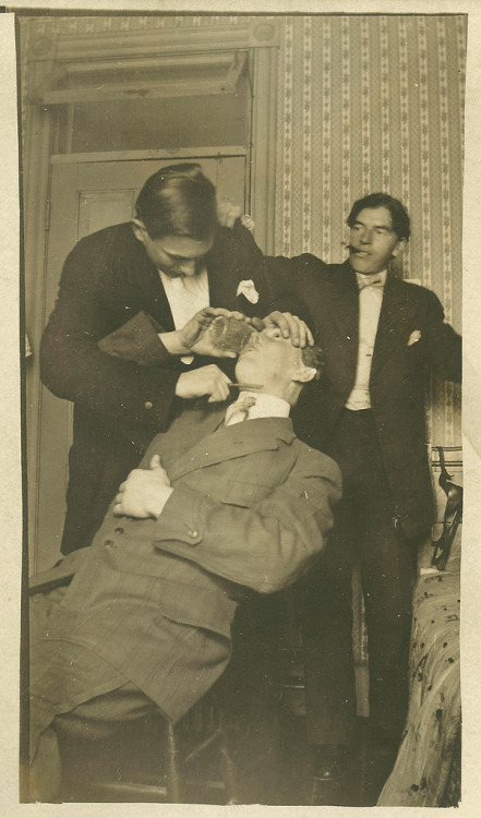 weirdvintage:A man drinks while another man holds a straight...