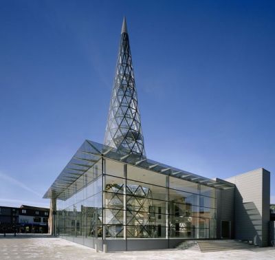 archatlas:<br /><br /><br /><br />The Glass Centre in Lommel<br /><br />The Glass Centre, Flemish Centre for Modern Art, designed by Philippe Samyn and Partners has been constructed along the length of the “De Vryheyt” passage, right in the heart of the town of Lommel. On “Dorp” square it completes the cultural ensemble formed by the Aerts house and the regional tourist centre. In the “De Vryheyt” passage, a new glass gallery links “Dorp” square with the “De Adelberg” cultural centre and its future theatre.The nature of the project required us to design a glass building, and it has been designed in such a way that the space it provides blends in seamlessly with the art it displays and produces, forming a unified whole. Furthermore, the structure emphasises the Glass Centre’s multifunctionality (education, information, services, exhibitions and glass production).