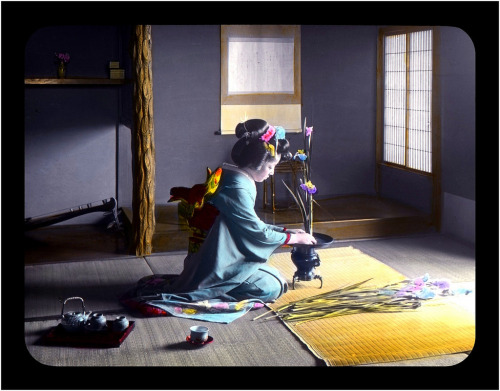 GEISHA ARRANGING FLOWERS BY THE LIGHT OF AN OPEN DOOR – Published by T. TAKAGI (by Okinawa Soba)