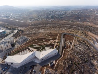 archatlas:<br />Palestinian Museum in Birzeit<br />The landscape of the Palestinian Museum by Heneghan Peng has the ‘worked’ quality of a city; every element of it has been touched and tells a story of intervention, production, culture, environment, commerce. Like a city, the terraced landscape has embedded within it its history. The approach to the Palestinian Museum is to draw on this history of the terraced landscape, embedding the museum into its immediate site and drawing from this site to tell a larger story of a diverse culture.<br />The cascade of terraces tells a diversity of stories, citrus brought in through trade routes, native aromatic herbs, a rich and varied landscape with connections east and west. The building itself emerges from the landscape to create a strong profile for the hilltop both integrated into the landscape yet creating an assertive form that has a distinctive identity.<br /><br /><br />Follow the Source Link for images sources and more information. <br /><br /><br />