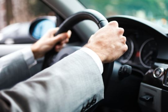 Mãos do motorista segurando o volante do carro