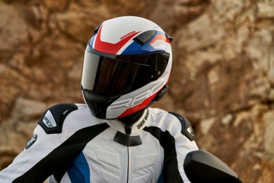 motociclista com capacete bmw motorrad branco com detalhes em vermelho e azul