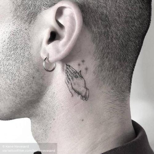 Small praying hands tattoo located behind the ear