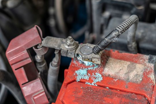 bateria de carro vermelha mostra acumulo de oxidacao zinabre ao redor do terminal