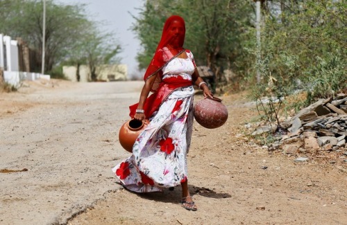 fotojournalismus:A woman carries earthen pots to fill them with...