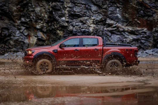 ford ranger 2020 storm na cor vermelha vista pela lateral andando na lama com rochas ao fundo