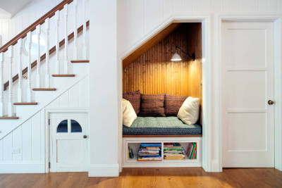 Cozy Reading Nook under Stairs in Clean, White Contemporary next to Miniature Door leading to a Kids Hideaway [2560 x 1706]