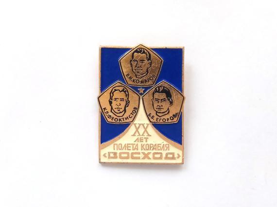 Vintage pin commemorating 20 years of the flight of Voskhod spacecraft in 1964. Voskhod was the first ever multi-person spacecraft (3 cosmonauts). The pin features three cosmonauts who were the team of Voskhod: Vladimir Komarov, Konstantin...