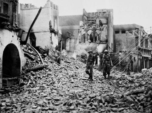 worldhistoryfacts:British soldiers walk through a destroyed area...