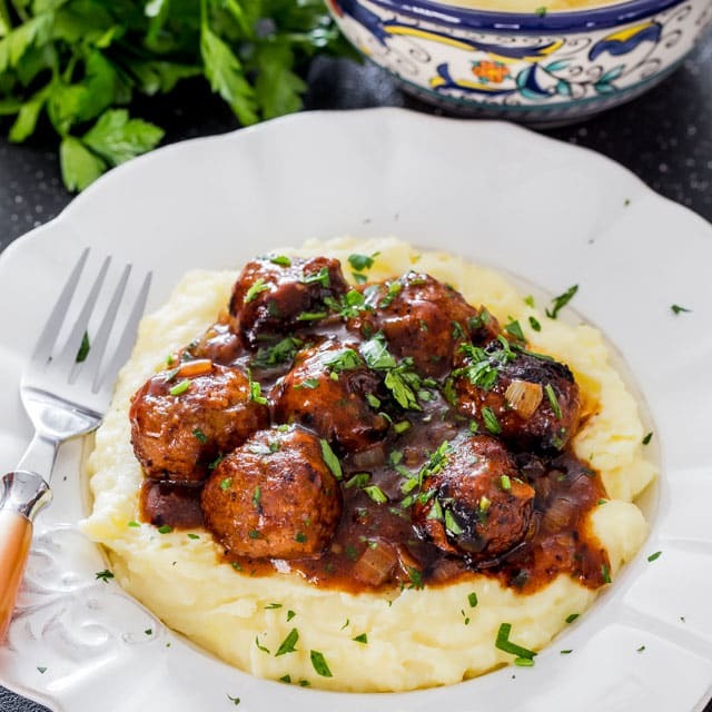 a plate of mashed potatoes and salisbury steak meatballs and gravy