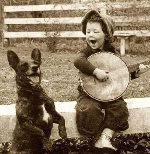 A young boy playing the banjo with his best friend, 1920. Check this blog!