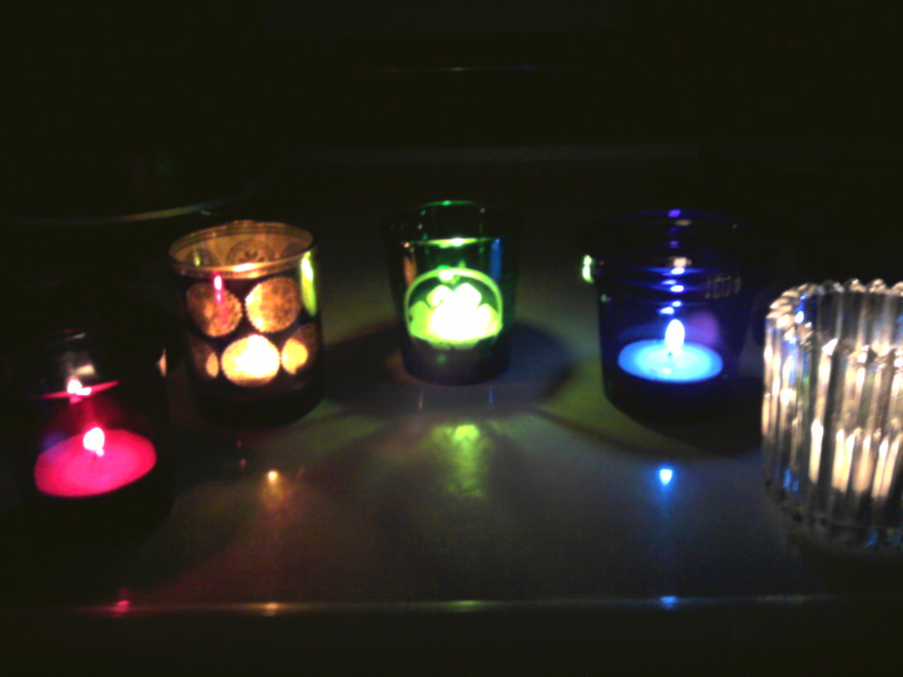 five votive candleholders arranged in an arc, ambient light off