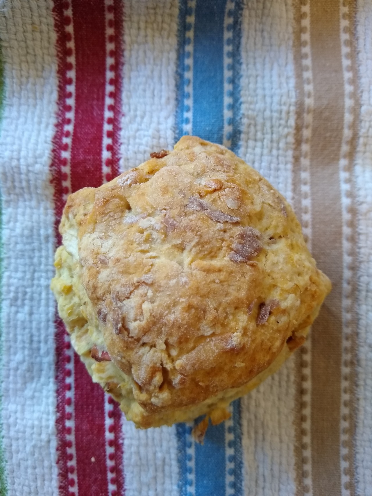 An overhead shot of an apple scone on a multicolored striped dishtowel.