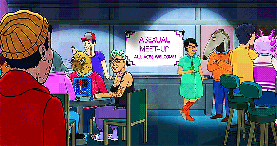 Gif of Todd, a white man with stubble, blue hair, a yellow beanie, a red hoodie and gray jogger trousers with white stripes, looking over a different people near a sign that says "ASEXUAL MEET-UP ALL ACES WELCOME!" in purple lettering. Also, a woman of color with turquoise hair, a black top and blue trousers, waves Todd over, from the show Bojack Horseman