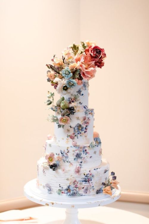 A beautiful floral four-tier wedding cake made for a...