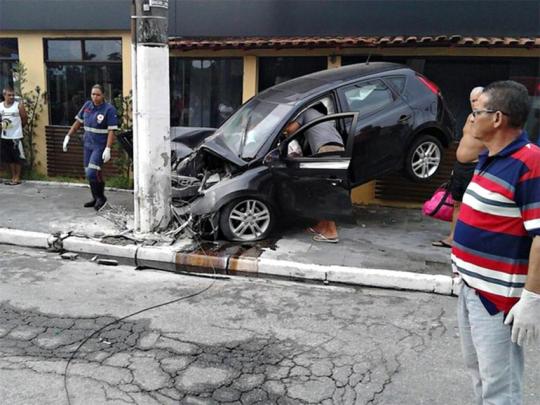 acidente transeuntes olham hyundai i30 preto batido no poste em rua do guaruja foto corpo de bombeiros