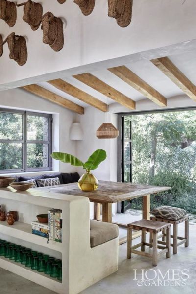 Open plan kitchen diner in a traditional Spanish cottage on the mountainside of Mallorca. Lime-plastered walls add to the traditional feel along with the seventies Mallorcan stools made from leather and wood which are the only furnishings that remain from the original house. This is complemented by locally sourced textiles and accessories such as vintage glassware and traditional woven-palm pieces