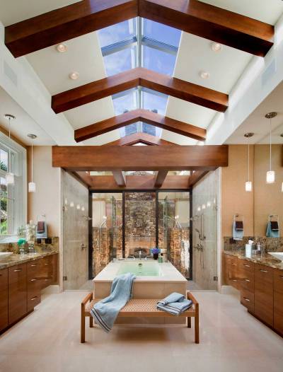 His and hers bathroom with dual showers that look onto a stone fireplace. [1597 × 2100]