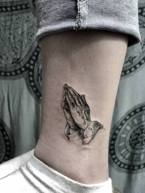 Minimalist praying hands tattoo on the wrist