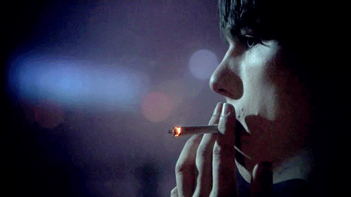  A boy smokes a cigarette in his room while he waits for his crush to send him a whatsapp message