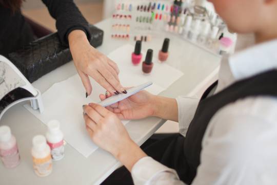 Manicurist polishing finger nails at beauty salon, Harajuku, Tokyo, Japan.