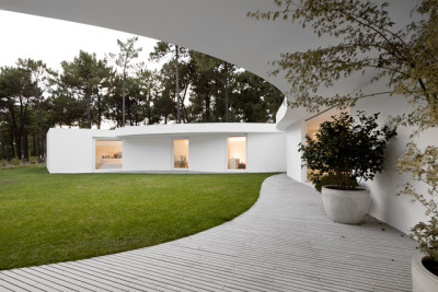 ombuarchitecture:<br /><br />House in Aroeira<br />Due to the absence of fences, the hexagonal shape of the plot is not clear and the ground blends with the surrounding pinewoods. The house occupies the maximal area of construction, concentric to the six-sided plot. Disposed round a courtyard to which every space converges, its peculiar form finds a precise boundary in the outline of the canopy. Service areas provide geometry and stability to the main spaces.<br />By Aires Mateus<br />Photos by FG+SG