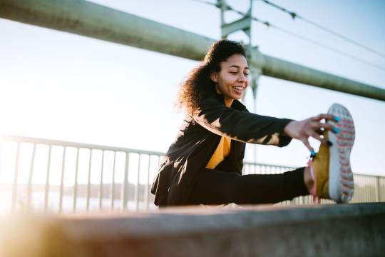 A young mixed race woman stretches before an early jog in the city of Tacoma, Washington. Her running takes her across the Tacoma Narrows bridge, with a running path spanning the Puget Sound from Tacoma to Gig Harbor.