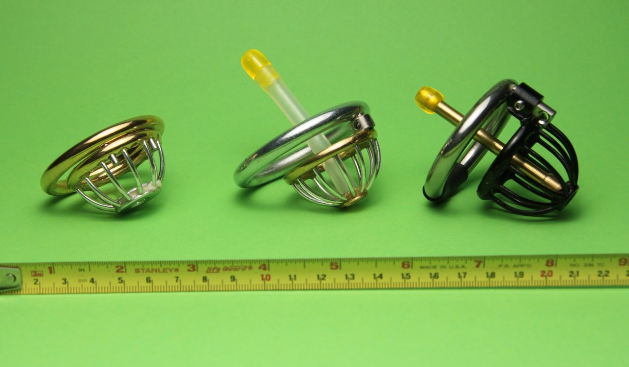Here are the latest three chastity devices my bf trox has built on my request. The oldest is the black one on the right side with a length of 50 mm and a solid brass plug protruding 28 mm.The one in the middle is 37 mm in total length and its flexible silicone plug protrudes 40 mm. Both are very comfortable to wear as my bf trox reports and due to the plugs no pullout is possible.The left one is a very short prototype with a variable length of 36 mm to 31 mm made from brass and aluminium. But at the shortest setting the remaining space between the A ring and cage is too less to ensure enough blood circulation to the scrotum and balls trox reported after a short first trial. So there a modification of the A ring is necessary. I want to keep him chaste and even shorter by the time, but I really do not want to castrate my beloved honey. Later on a plug for security will be fitted.After a short release for the shooting trox had to clean in the shower under my supervision and I locked him up again in the cage in the middle. On this occasion I could measure a reduction of his flaccid member length from 12 cm to 4 cm after a wearing time of one week. Funny to see when I showed him my naked boobs and pussy while he was showering without the cage his cock got hard but was only less than 12 cm in length. Before the procedure I measured a hard length of 16 cm on him. I will get him shorter!Youralphagirl Alina