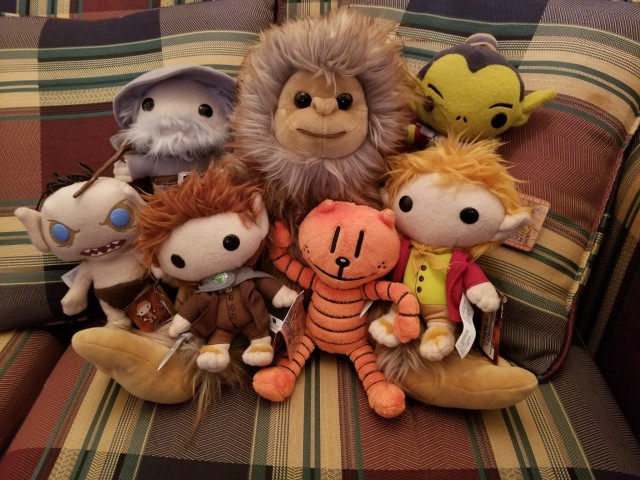 Plushies arranged in a happy lil pile. Center is a large Bigfoot and around him are the following characters: Gollum, Gandalf, Frodo, Bilbo, and a goblin, from LOTR, and Petey the cat, from Dog Man.