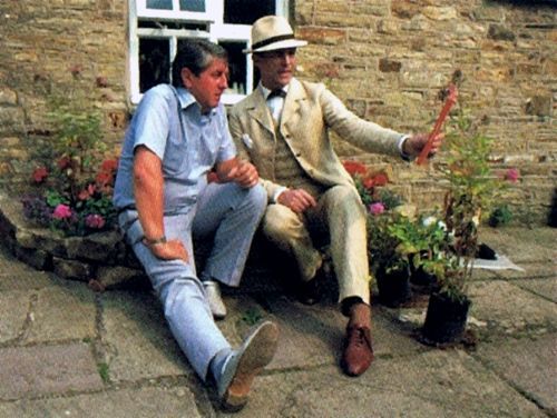 Jeremy Brett and unknown Granada Holmes crew member sitting.