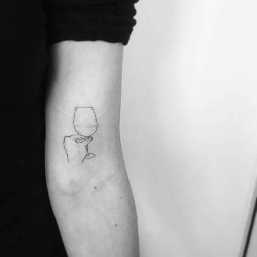 Tiny wine glass tattoo placed on the wrist,