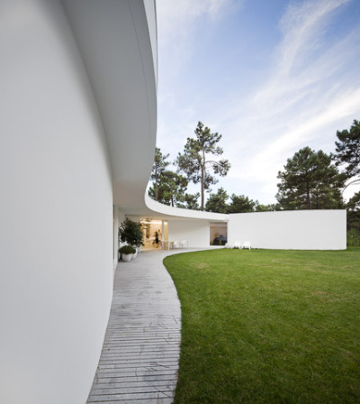 ombuarchitecture:<br /><br />House in Aroeira<br />Due to the absence of fences, the hexagonal shape of the plot is not clear and the ground blends with the surrounding pinewoods. The house occupies the maximal area of construction, concentric to the six-sided plot. Disposed round a courtyard to which every space converges, its peculiar form finds a precise boundary in the outline of the canopy. Service areas provide geometry and stability to the main spaces.<br />By Aires Mateus<br />Photos by FG+SG