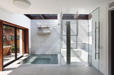 Sauna with two-level seating and a metal shower column next to a sunken tub under a glass ceiling in this home in Rio. [1559 × 1034]