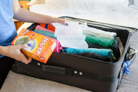 person is packing suitcase with dryer sheet to ready for the travel