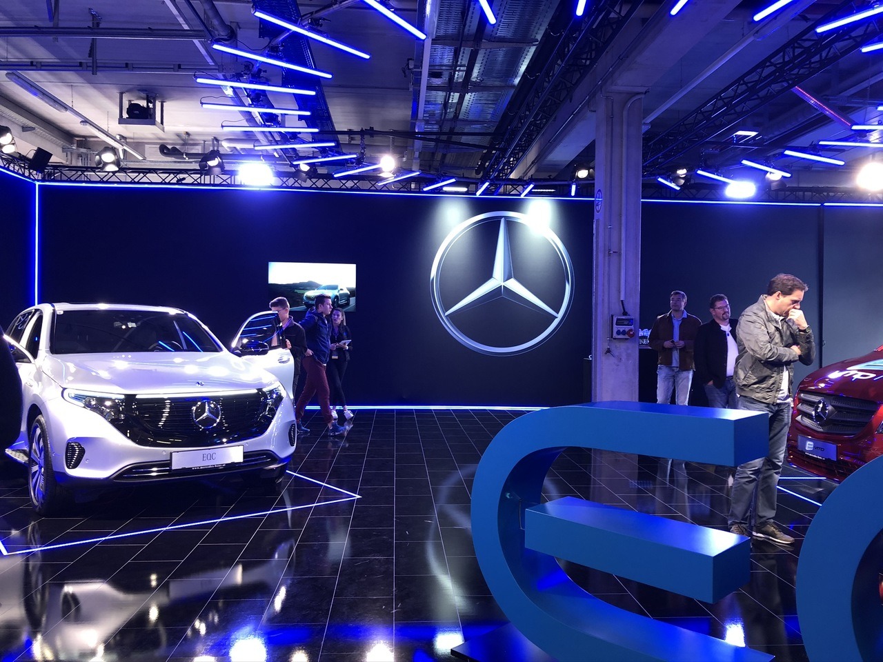 Mercedes-Benz EQ Showroom mit dunklen Wänden und Boden und blauen LEDs als akzentfarbe (wie in den Autos selbst). Zu erkennen ist die EQC Klasse und die elektrische Version des Vito.