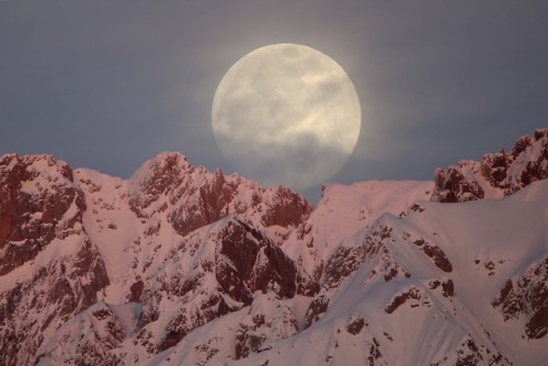 fotojournalismus:Full moon rises behind snow-covered mountains...