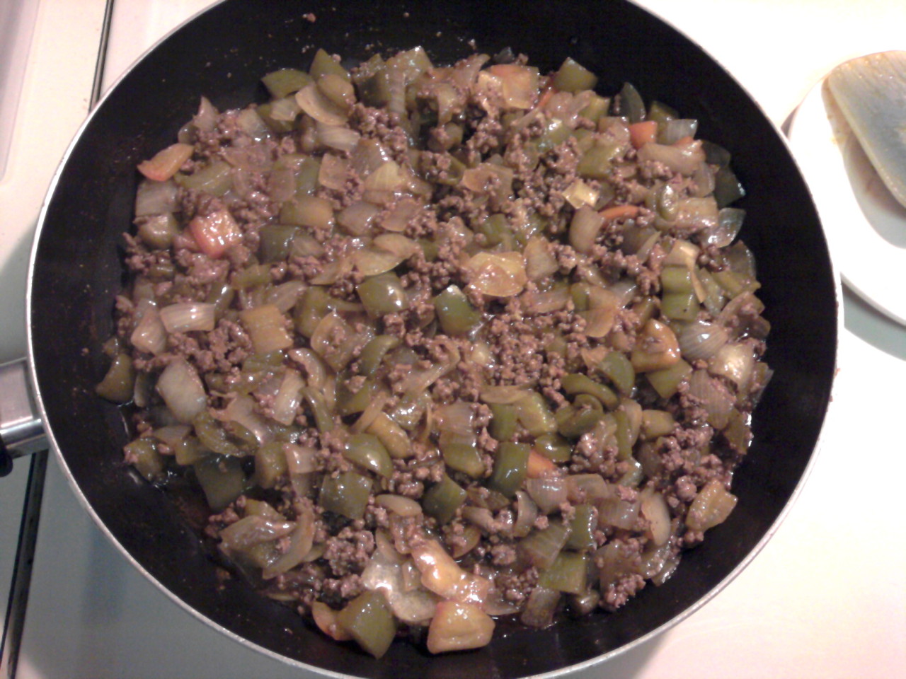 mix of ground beef, bell pepper, and onion in a large frying pan