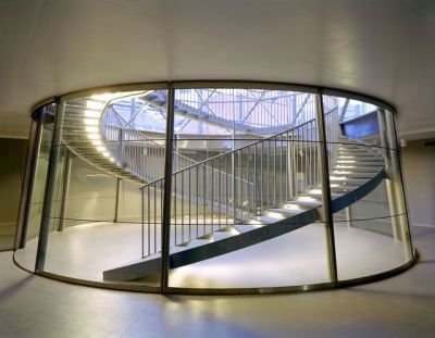 archatlas:<br /><br /><br /><br />The Glass Centre in Lommel<br /><br />The Glass Centre, Flemish Centre for Modern Art, designed by Philippe Samyn and Partners has been constructed along the length of the “De Vryheyt” passage, right in the heart of the town of Lommel. On “Dorp” square it completes the cultural ensemble formed by the Aerts house and the regional tourist centre. In the “De Vryheyt” passage, a new glass gallery links “Dorp” square with the “De Adelberg” cultural centre and its future theatre.The nature of the project required us to design a glass building, and it has been designed in such a way that the space it provides blends in seamlessly with the art it displays and produces, forming a unified whole. Furthermore, the structure emphasises the Glass Centre’s multifunctionality (education, information, services, exhibitions and glass production).