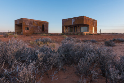 archatlas:<br /><br />Mexican Water Cabins DesignBuildBLUFF<br /><br /><br />The Mexican Water Chapter of the Navajo Nation partnered with Design Build BLUFF (and University of Colorado Students)  to construct two rentable cabins; with the idea that tourism dollars otherwise lost outside the boundaries of the reservation could rather stay and help encourage the local economy. Influenced by the landscape and distant views of the Blue Mountains and Monument Valley, the design led to the development of two “sibling” cubes. One rests on the landscape while the other emerges from it. <br /><br /><br />Images and text via DesignBuildBLUFF<br /><br /><br />