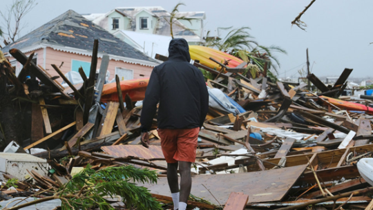 Men is walking on the destroyed home by the Hurricane Dorian
