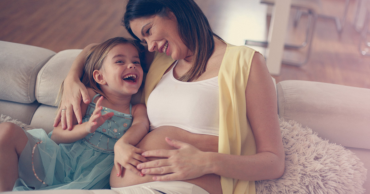 Pregnant mom seating with her little girl - Joy of Life Surrogacy