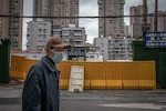 Un homme portant un masque protecteur passe devant une clôture de sécurité dans les rues de Wuhan le 30 mars 2020.