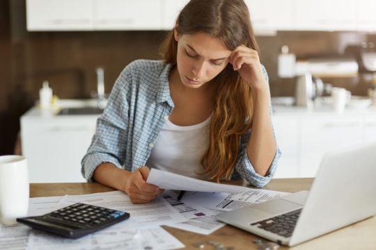 mulher preocupada pagando contas taxa delicenciamento atrasada como pagar impostos tributos shutterstock